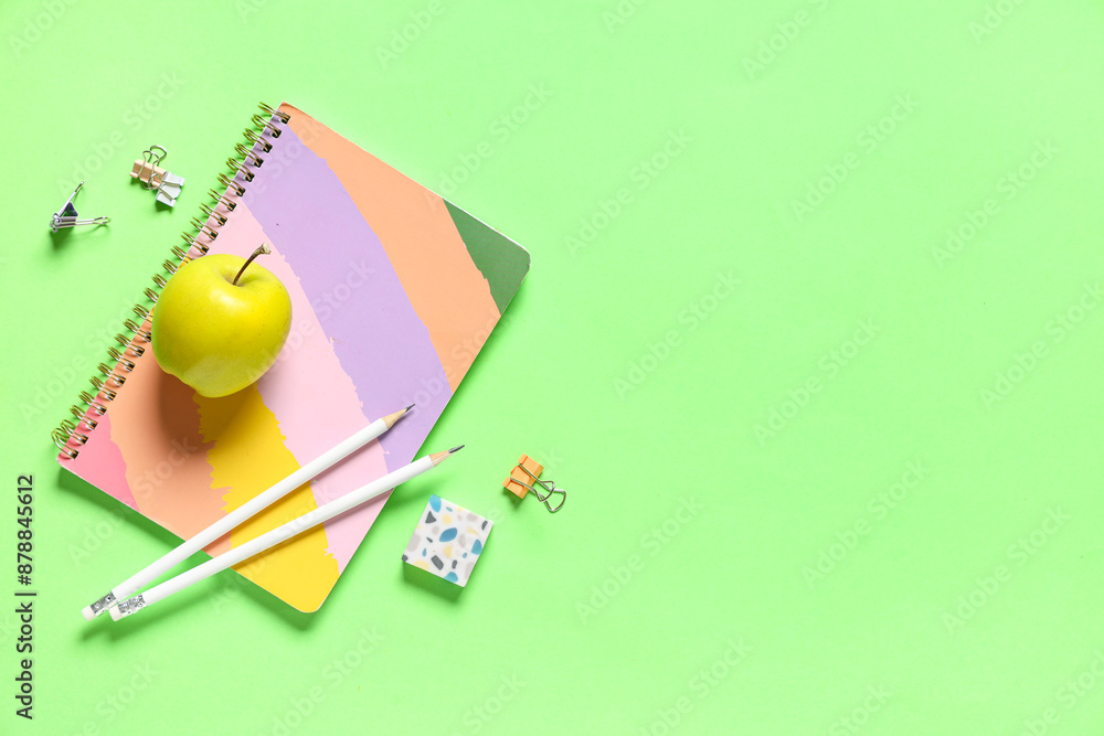 Tasty apple and different school stationery on green background Tasty apple and different school stationery on green background