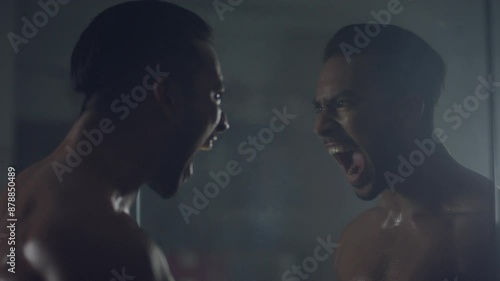 Man screaming while looking at himself in the mirror