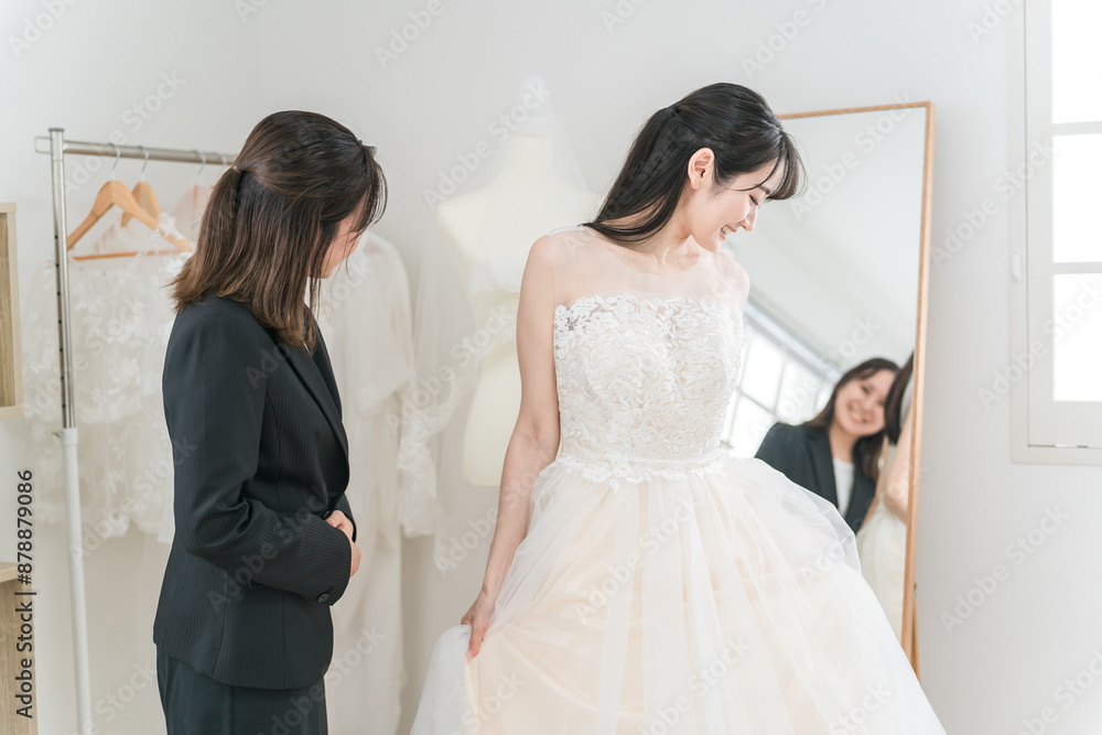 Naklejka premium 結婚式の準備でウェディングドレスの衣装合わせをするアジア人女性（試着・フィッティング） 