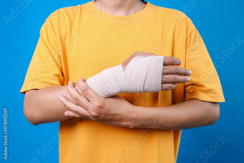Closeup Of Injured Man Wearing Medical Support Brace And Elastic Bandage Isolated On Blue Background 