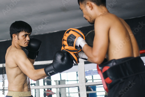 Two Asian Fighters Man Practices Together Wearing Boxing Gloves And Punching Pad In Boxing Ring