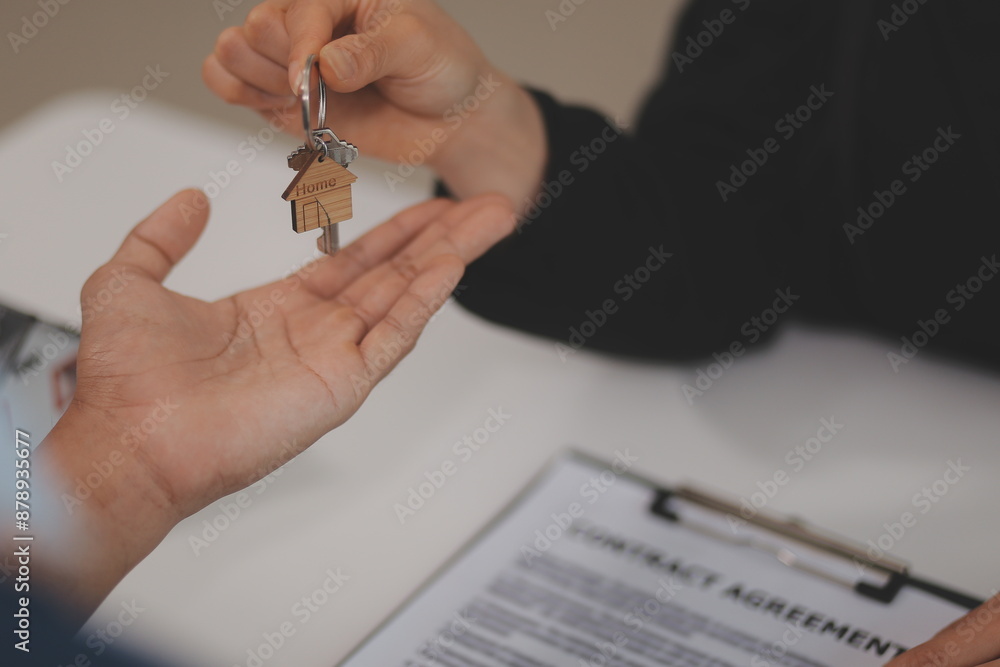 Fototapeta premium Estate agent giving house keys to client after signing agreement contract real estate with approved mortgage application form, concerning mortgage loan offer for and house insurance.