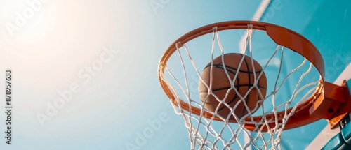 Basketball swishing through the hoop under clear blue sky, symbolizing success and achievement in a vibrant sports scene. © nattapon98