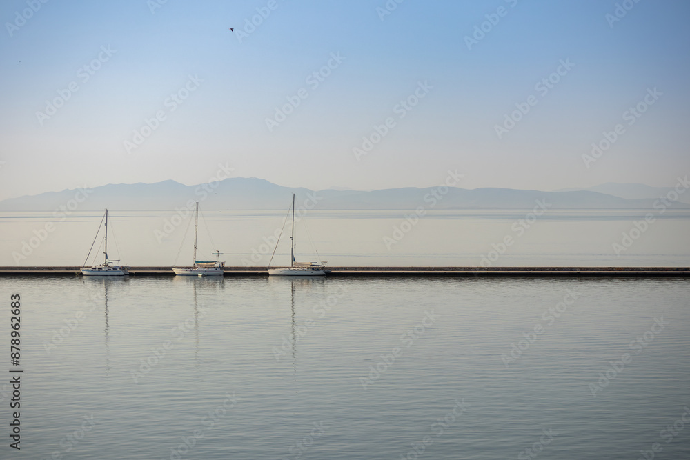 three white boats with masts docked in the harbor on a calm sea three white boats with masts docked in the harbor on a calm sea