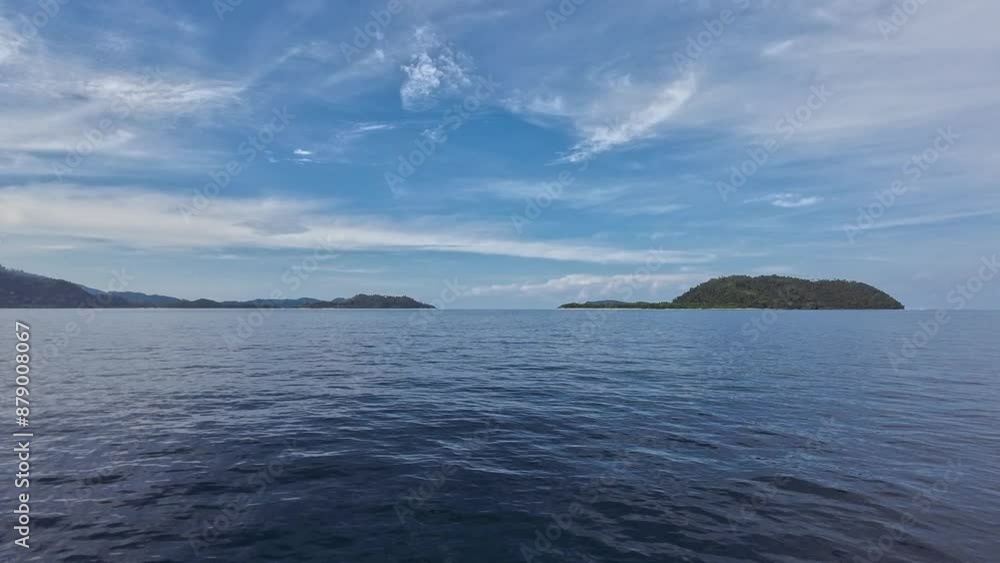 island in the sea. blue and partly cloudy sky. forward motion. padang, indonesia island in the sea. blue and partly cloudy sky. forward motion. padang, indonesia
