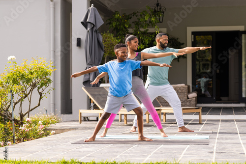 African American father practices yoga outdoors with his son and daughter photo