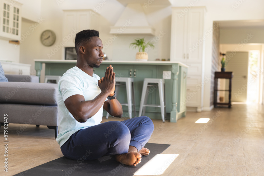African american man practicing yoga meditation sitting on floor at home, copy space African american man practicing yoga meditation sitting on floor at home, copy space