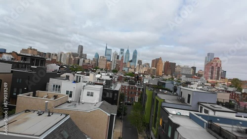 Modern row houses near downtown Philadelphia skyline. Aerial FPV drone shot fast and low over rooftops in urban USA city. photo