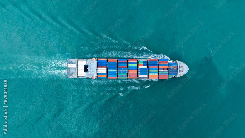 Fototapeta premium Cargo container ship carrying container and running in the ocean near international container port customs shipyard sea port concept smart logistic service. transportation logistics trading..