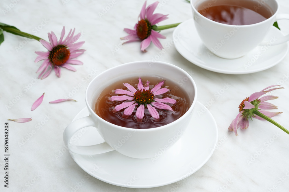 Tea with Echinacea in a white cups on marble table. Echinacea drink preparation concept. Echinacea tea. Side view, copy space. Tea with Echinacea in a white cups on marble table. Echinacea drink preparation concept. Echinacea tea. Side view, copy space.