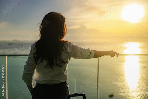 Attractive woman in beautiful beach hotel looking to beautiful view of a golden sky and the sun's rays shining on the sea, Big sun, enjoying freedom and life. Calmness, Relaxation.