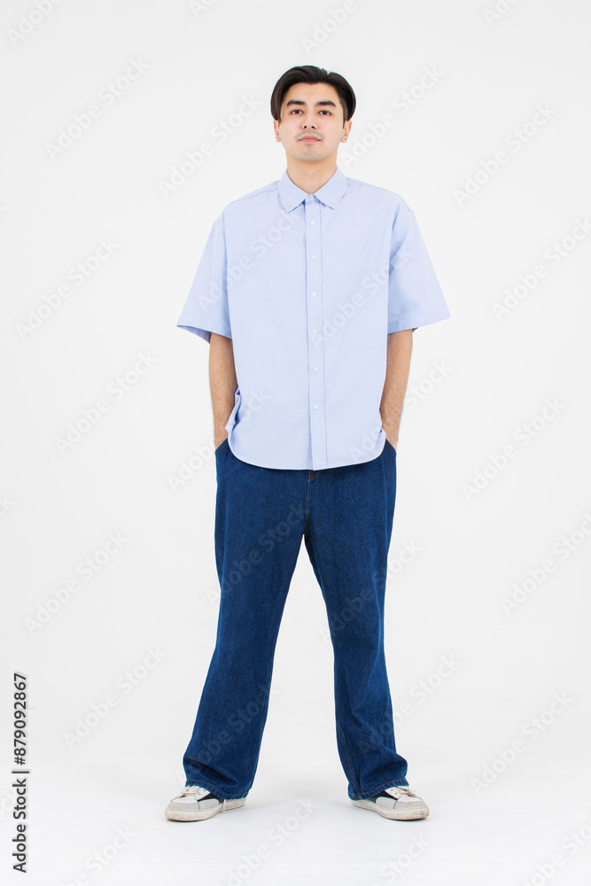 Fototapeta premium Portrait of asian male confidence charming handsome young guy, Wearing blue collar shirt and jeans posing relaxed looking attractive standing on white background studio - isolated