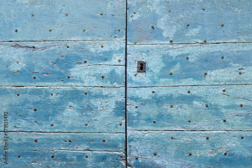 Fotografi Background of two closed old blue painted, weathered and peeling wooden doors wi