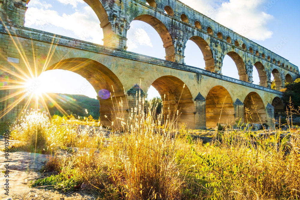Fototapeta premium The magnificent Pont du Gard backlit by the setting sun. Photograph taken in Occitanie, France