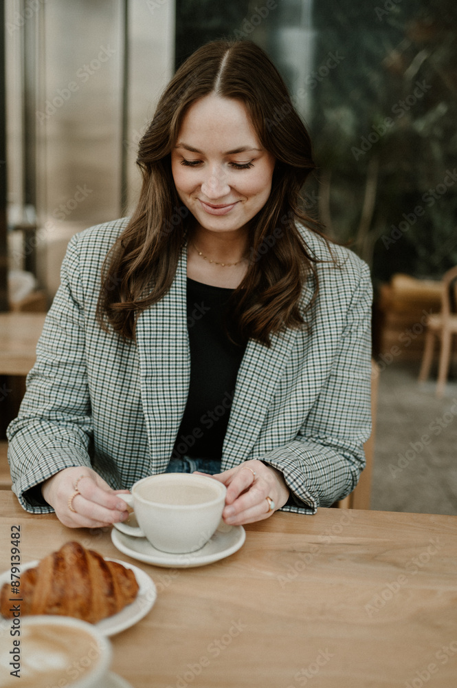 Woman enjoying coffee at a cafe with a croissant. Woman enjoying coffee at a cafe with a croissant.