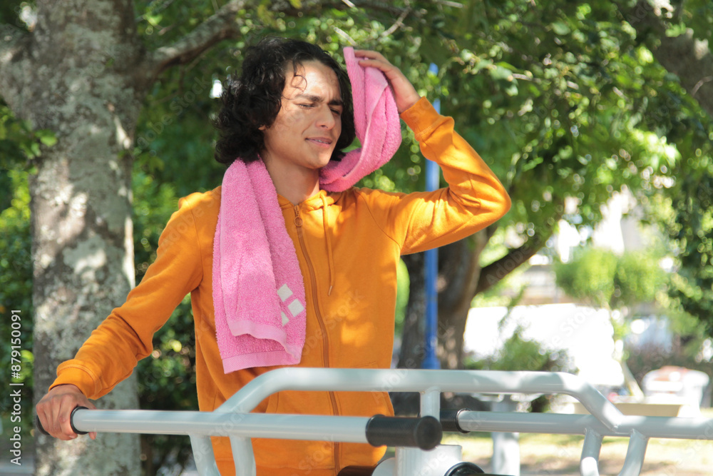 Naklejka premium young man in training equipment in the park fatigued making a break