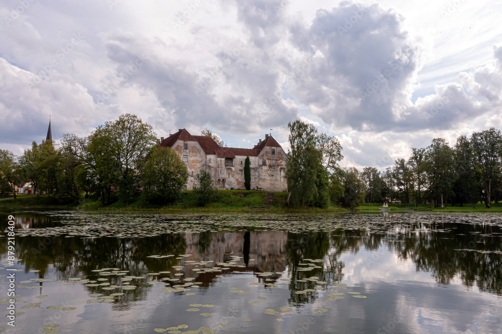 Historic Stone Castle Reflecting in Tranquil Latvian Lake on Cloudy Summer Day Historic Stone Castle Reflecting in Tranquil Latvian Lake on Cloudy Summer Day