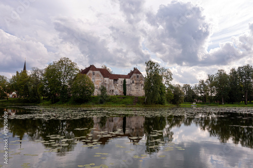 Historic Stone Castle Reflecting in Tranquil Latvian Lake on Cloudy Summer Day © ako-photography