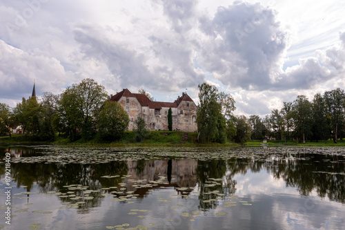 Historic Stone Castle Reflecting in Tranquil Latvian Lake on Cloudy Summer Day