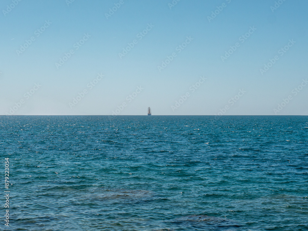 Fototapeta premium Frigate on horizon line in open sea front view