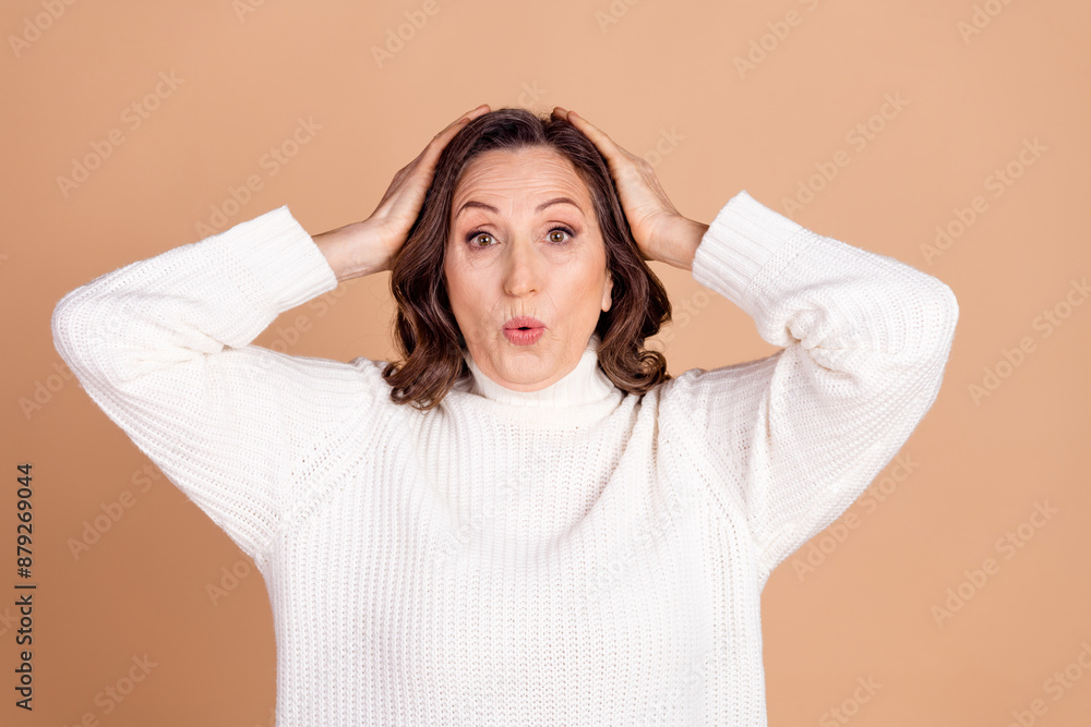 Photo of cheerful glad senior woman wear white stylish clothes arm touch head isolated on beige color background Photo of cheerful glad senior woman wear white stylish clothes arm touch head isolated on beige color background