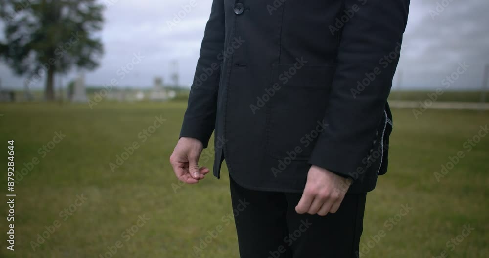 Man in black suit attending funeral standing in cemetery. Man in black suit attending funeral standing in cemetery.