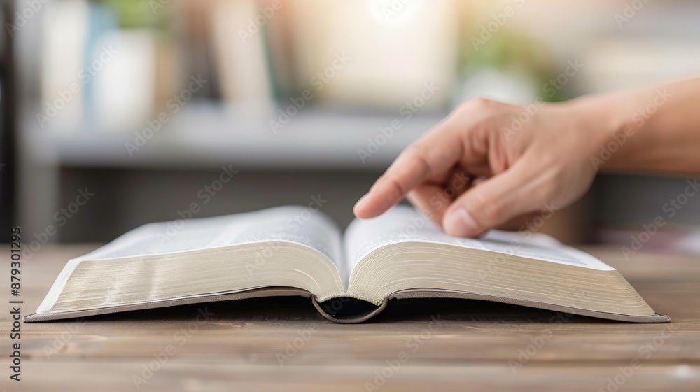 A hand points to text in an open book, with warm bokeh lights in the background A hand points to text in an open book, with warm bokeh lights in the background