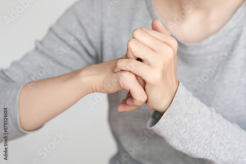 Close-up of a person cracking their knuckles. The image shows hands in action, wearing a grey long-sleeved shirt against a plain background. © Oporty786