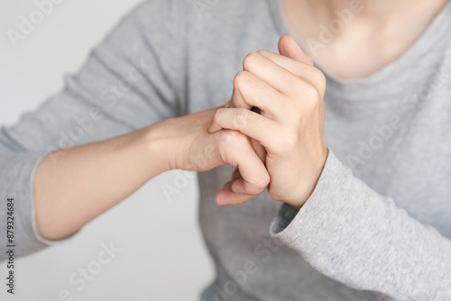 Close-up of a person cracking their knuckles. The image shows hands in action, wearing a grey long-sleeved shirt against a plain background.