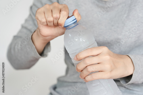 Fotografie Hands opening a plastic bottle of water