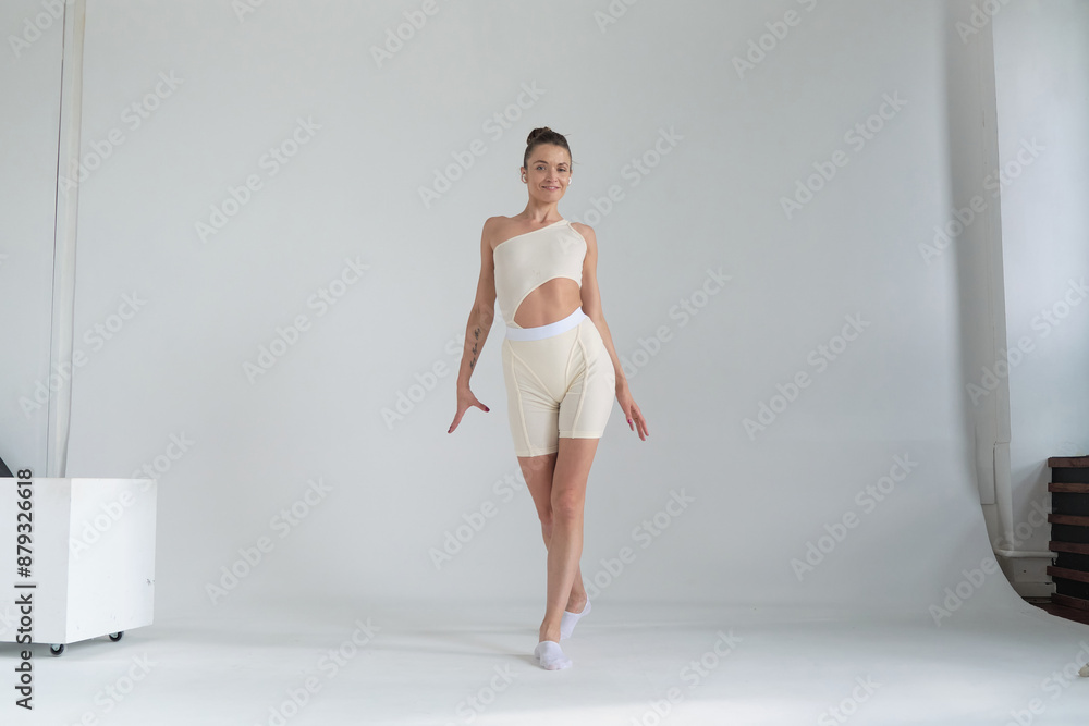 Woman in a stylish beige outfit, executing a dance move with precision and elegance in a bright studio. Concept: Showcasing the integration of fashion and fitness, encouraging an active and stylish Woman in a stylish beige outfit, executing a dance move with precision and elegance in a bright studio. Concept: Showcasing the integration of fashion and fitness, encouraging an active and stylish