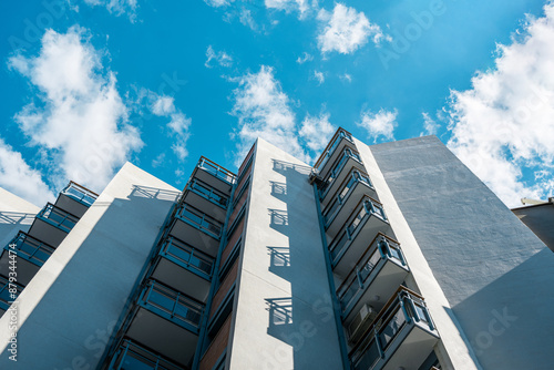 Low-angle view of a modern building with balconies, set against a vibrant blue sky. Contemporary architecture concept