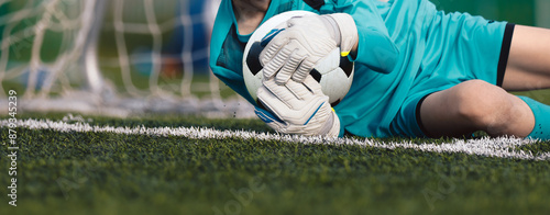 Soccer goalkeeper holding a soccer ball tight to the chest. Football training for young goalies