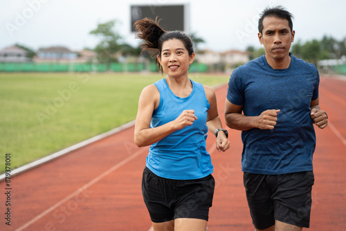 Asia mature woman and man runner training on racetrack and field 