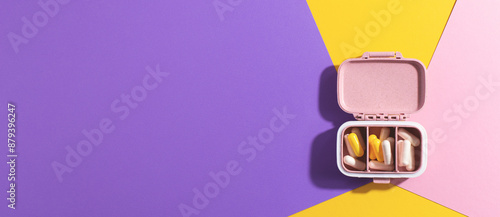 Medical, pharmaceutical web banner with pills and tablets in open pillbox on colourful background. Creative healthcare and wellness concept for travel.