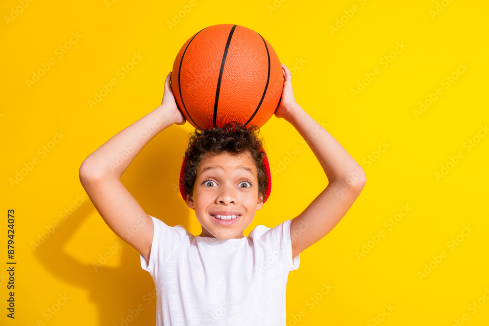 Photo portrait of adorable little boy raise basketball ball dressed stylish white garment isolated on yellow color background Photo portrait of adorable little boy raise basketball ball dressed stylish white garment isolated on yellow color background