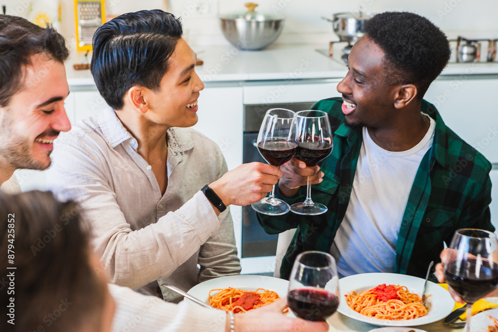 Group of friends toasting red wine glasses during lunch in kitchen Group of friends toasting red wine glasses during lunch in kitchen