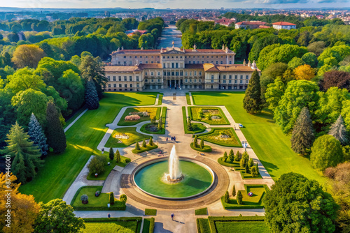 Breathtaking aerial view of the Royal Villa of Monza, showcasing its stunning architecture, lush green gardens, and majestic fountain, surrounded by tranquil trees.