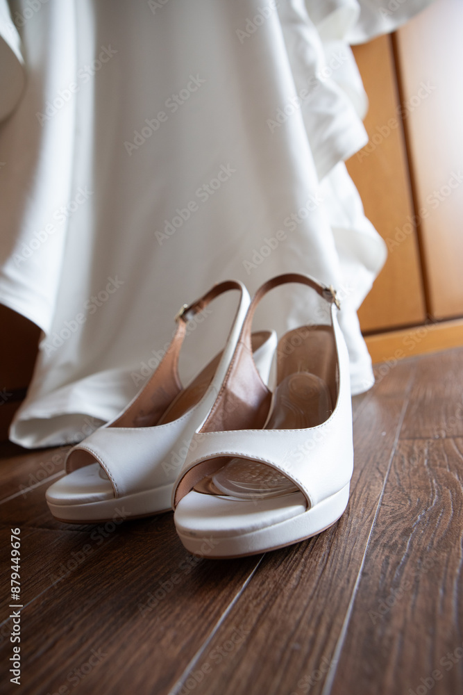 Elegant white bridal shoes resting under wedding dress Elegant white bridal shoes resting under wedding dress