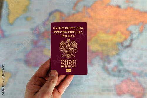 Man holding Poland passport in hand and world map in background