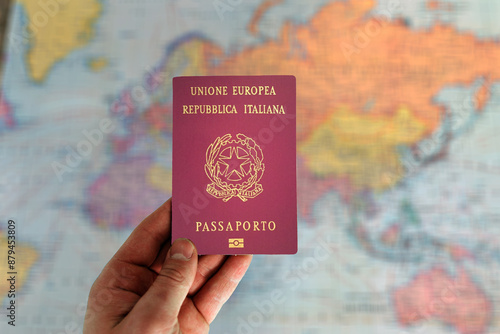 Man holding Italy passport in hand and world map in background