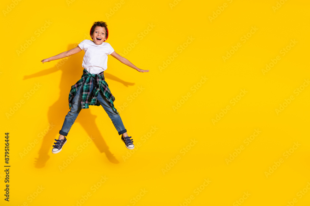 Full length photo of adorable little boy jump spread hands have fun dressed stylish white garment isolated on yellow color background Full length photo of adorable little boy jump spread hands have fun dressed stylish white garment isolated on yellow color background