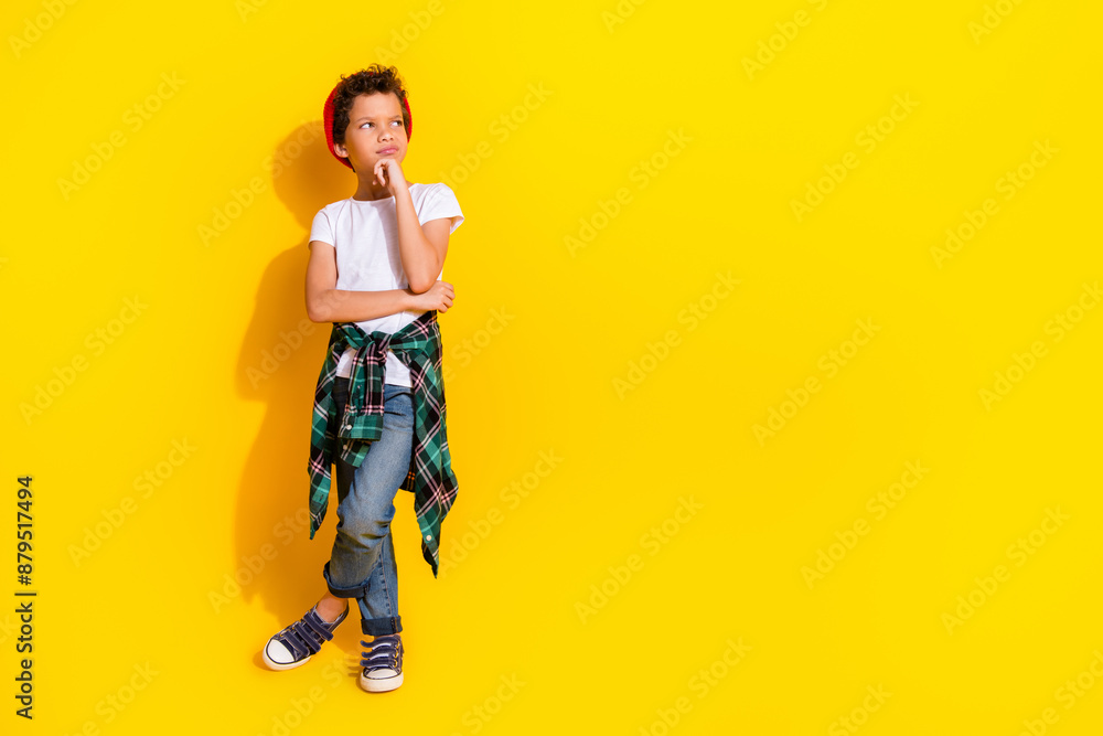 Fototapeta premium Full size photo of small charming boy look skeptical empty space wear trendy white outfit isolated on yellow color background