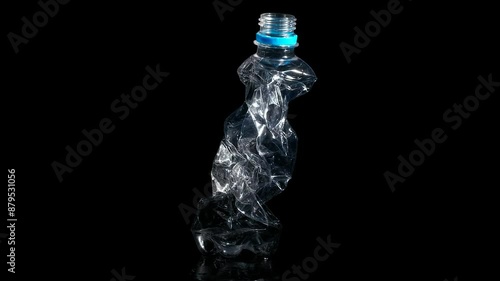 Squashed plastic bottle. A view of left plastic squashed bottle against black background. A concept of ecologycal plastic problem in the world. photo