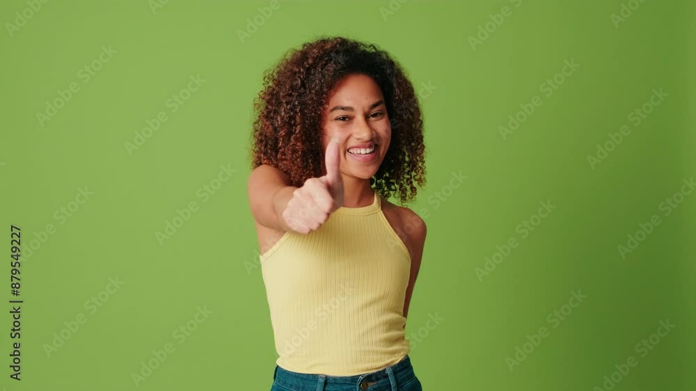 Young woman with a radiant smile doing thumbs up on a green background Young woman with a radiant smile doing thumbs up on a green background