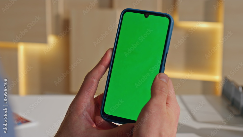 Man hand holding greenscreen smartphone in office closeup. Unrecognizable worker Man hand holding greenscreen smartphone in office closeup. Unrecognizable worker