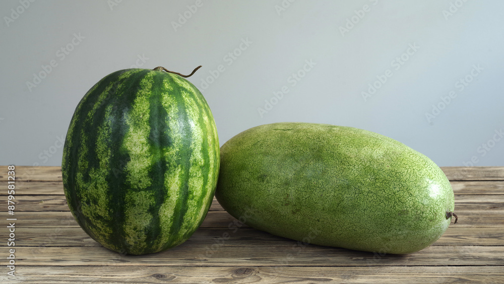 Two watermelons of different varieties lie on a wooden table. Two watermelons of different varieties lie on a wooden table.