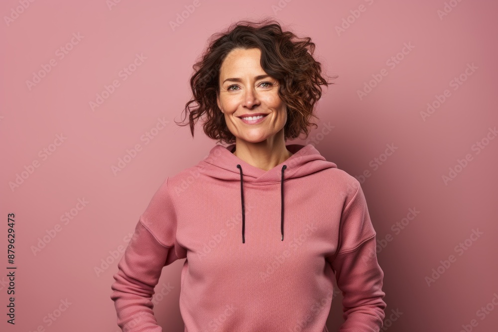Portrait of a satisfied woman in her 40s wearing a thermal fleece pullover while standing against solid color backdrop Portrait of a satisfied woman in her 40s wearing a thermal fleece pullover while standing against solid color backdrop