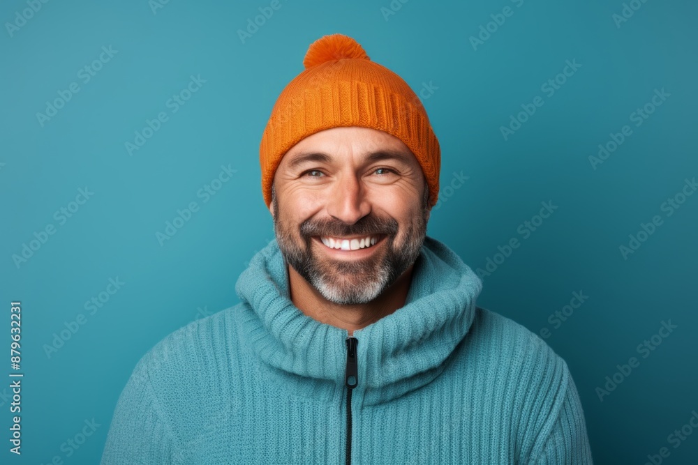 Portrait of a smiling man in his 40s dressed in a warm ski hat on solid color backdrop Portrait of a smiling man in his 40s dressed in a warm ski hat on solid color backdrop