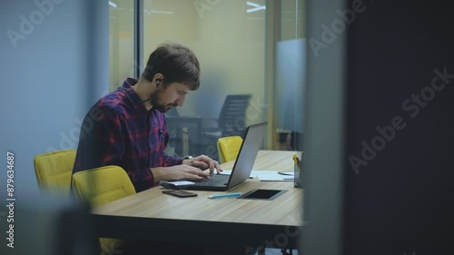 Young man using laptop computer, typing, working in office. Man working on laptop, remote work